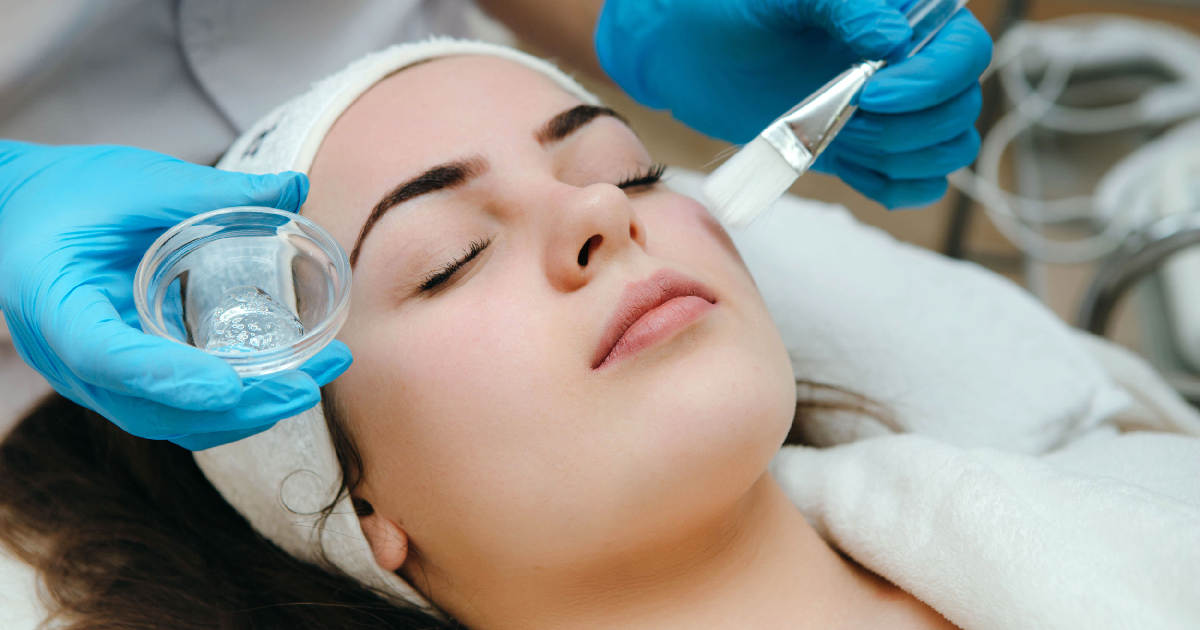Woman receiving a VI Peel in Lakewood CO, as a skincare professional applies the chemical solution to her face during the treatment session.