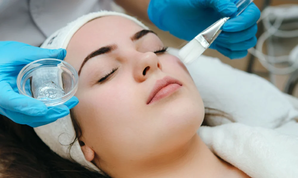 Woman receiving a VI Peel in Lakewood CO, as a skincare professional applies the chemical solution to her face during the treatment session.